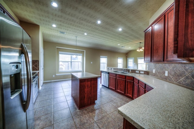 kitchen featuring lofted ceiling, a kitchen island, stainless steel appliances, decorative light fixtures, and ceiling fan