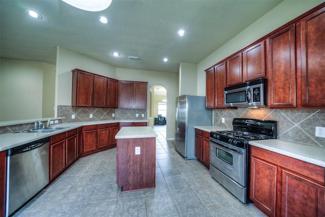 kitchen with a center island, sink, backsplash, appliances with stainless steel finishes, and light tile patterned floors