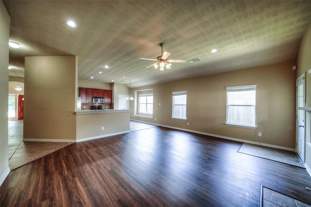 unfurnished living room featuring ceiling fan, a textured ceiling, and dark wood-type flooring