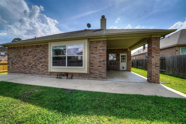 back of property with a yard and a patio