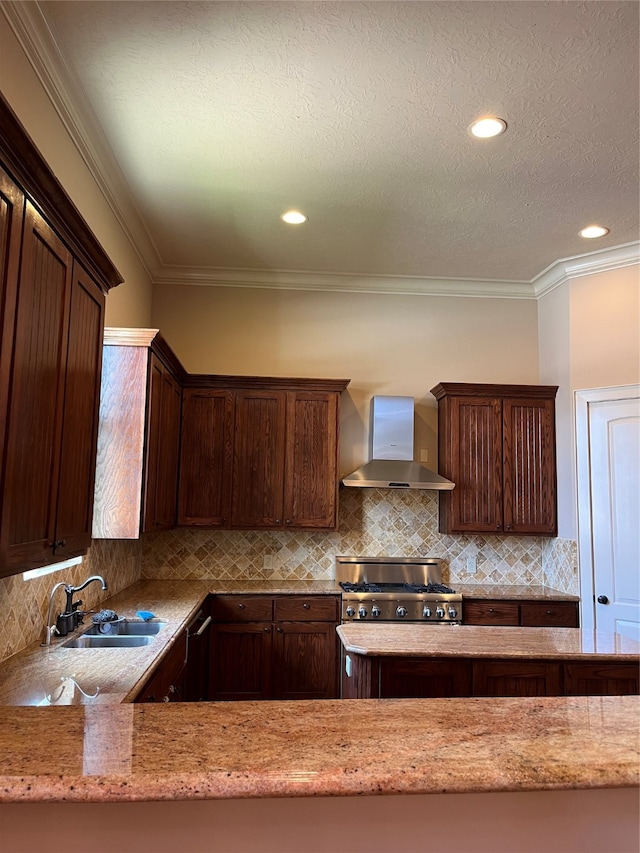 kitchen with ornamental molding, sink, wall chimney range hood, stainless steel range oven, and light stone countertops