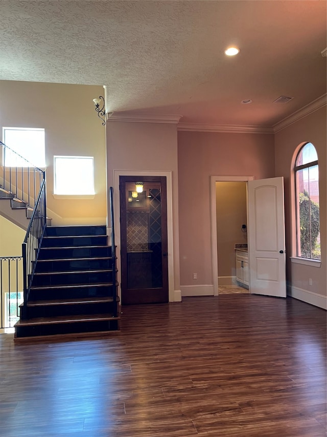 unfurnished living room with a textured ceiling, crown molding, and dark hardwood / wood-style flooring