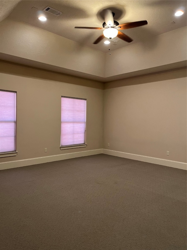 carpeted spare room with a textured ceiling, vaulted ceiling, ceiling fan, and a wealth of natural light