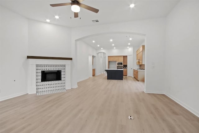 unfurnished living room with a tile fireplace, light hardwood / wood-style floors, and ceiling fan