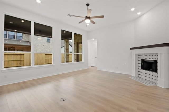 unfurnished living room featuring ceiling fan, light hardwood / wood-style floors, and a fireplace