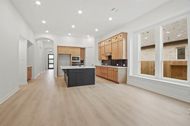 kitchen featuring a center island with sink, sink, light hardwood / wood-style flooring, built in microwave, and gas cooktop