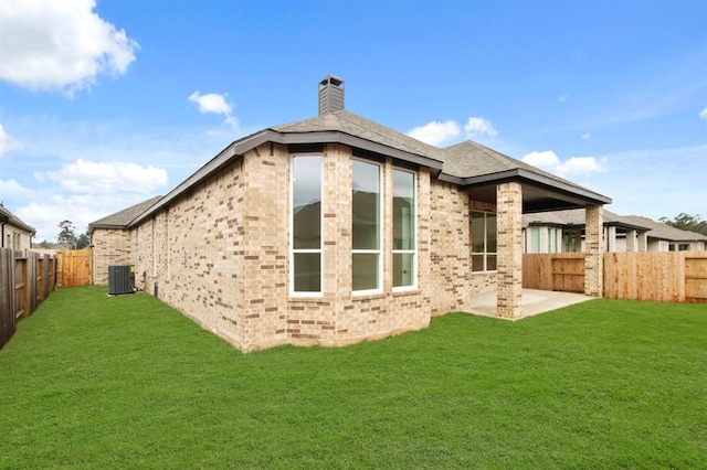 rear view of house with a lawn, central air condition unit, and a patio