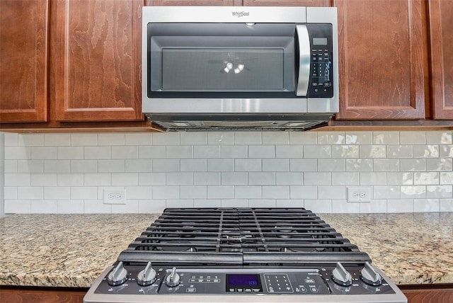 kitchen with light stone counters, decorative backsplash, and stainless steel appliances