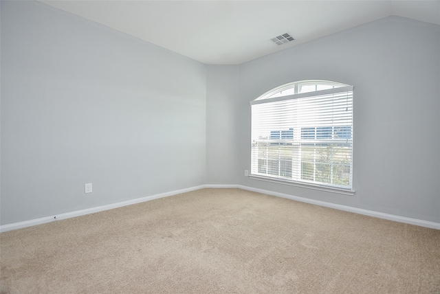 carpeted spare room with vaulted ceiling and a healthy amount of sunlight