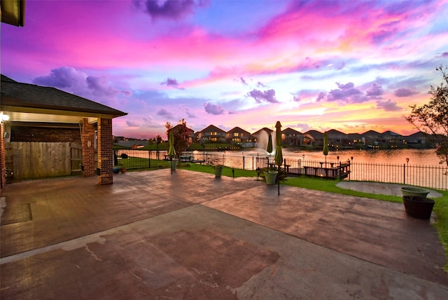 patio terrace at dusk featuring a water view