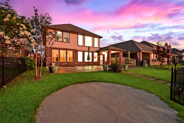 back house at dusk with a lawn