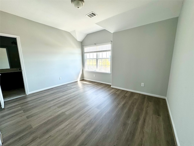 unfurnished room featuring vaulted ceiling and dark hardwood / wood-style flooring