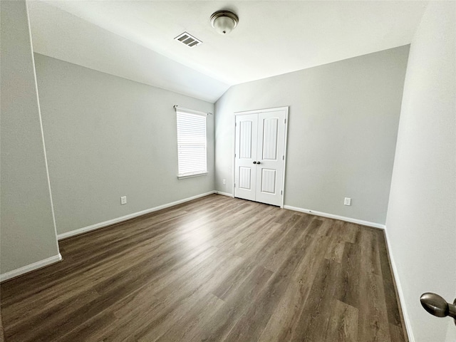 spare room featuring vaulted ceiling and dark hardwood / wood-style flooring