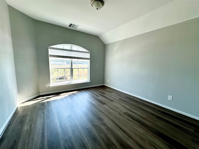 spare room with dark hardwood / wood-style floors and vaulted ceiling