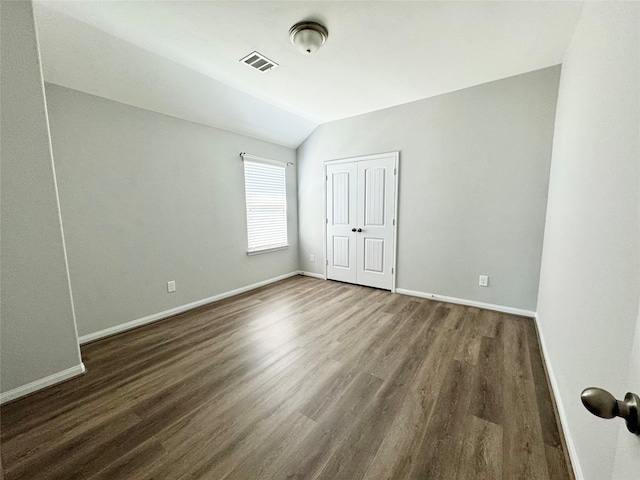 unfurnished room featuring lofted ceiling and dark hardwood / wood-style flooring