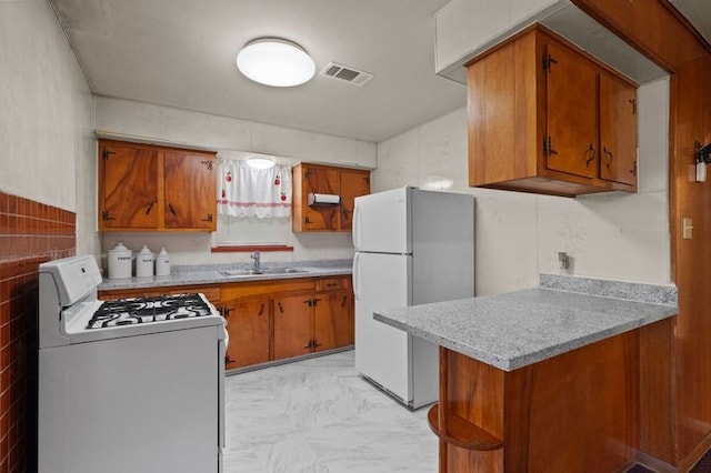 kitchen with sink, tile walls, kitchen peninsula, and white appliances