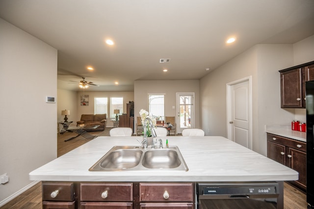 kitchen featuring ceiling fan, dark brown cabinetry, an island with sink, dishwasher, and dark hardwood / wood-style flooring