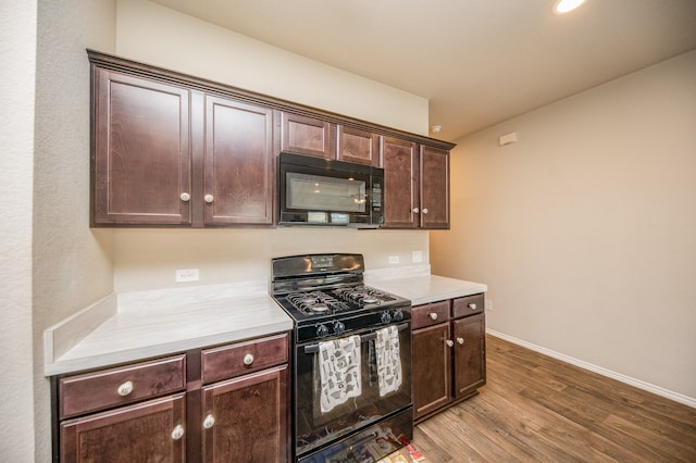 kitchen with dark brown cabinets, light wood-type flooring, and black appliances