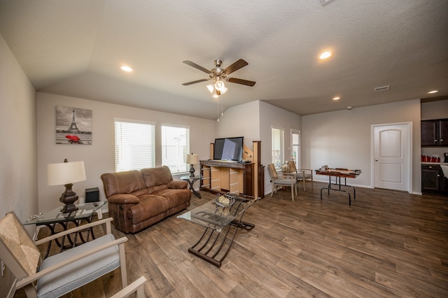 living room with ceiling fan, vaulted ceiling, a textured ceiling, and hardwood / wood-style floors