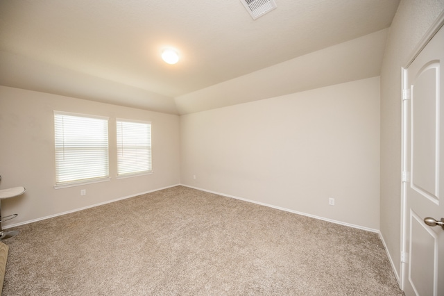 carpeted spare room with vaulted ceiling