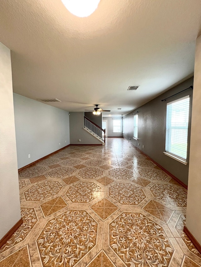 unfurnished living room with ceiling fan and a textured ceiling