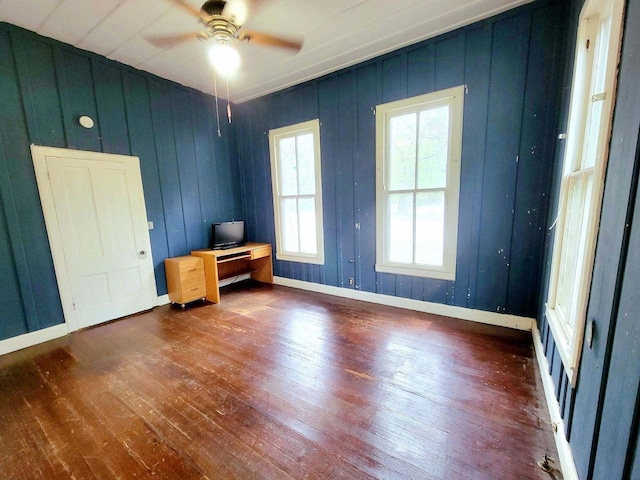 spare room with wooden walls, dark hardwood / wood-style floors, and ceiling fan