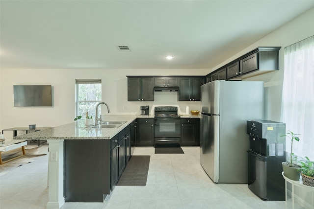 kitchen featuring light stone counters, light tile patterned flooring, sink, stainless steel refrigerator, and black electric range oven