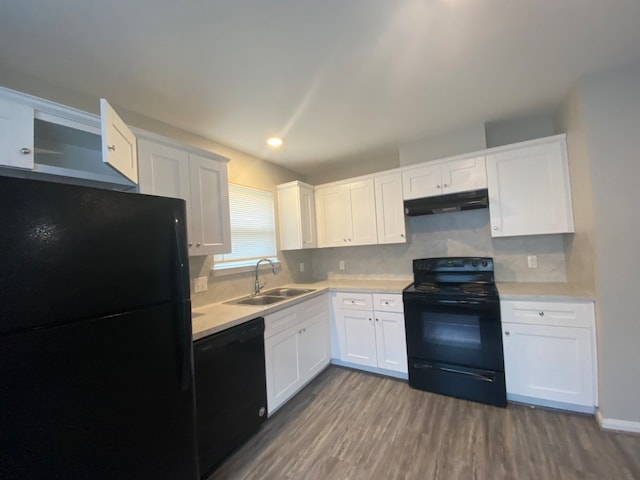 kitchen with decorative backsplash, white cabinetry, black appliances, hardwood / wood-style floors, and sink