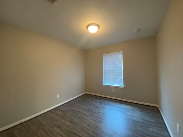 unfurnished room with a textured ceiling and dark hardwood / wood-style flooring