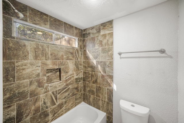 bathroom featuring toilet, tiled shower / bath, and a textured ceiling