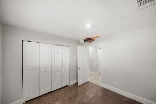 unfurnished bedroom with a closet and dark hardwood / wood-style flooring