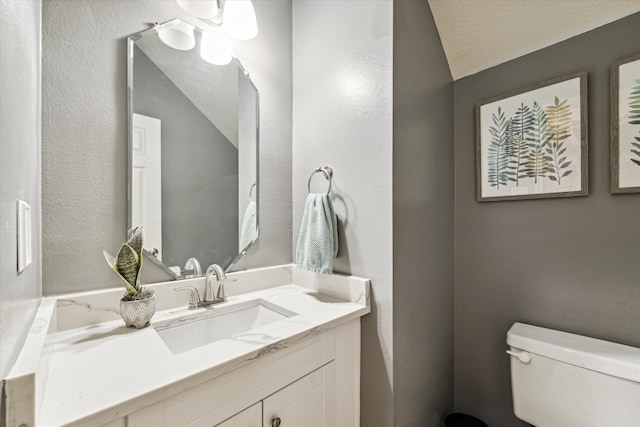 bathroom with toilet, vanity, and a textured ceiling