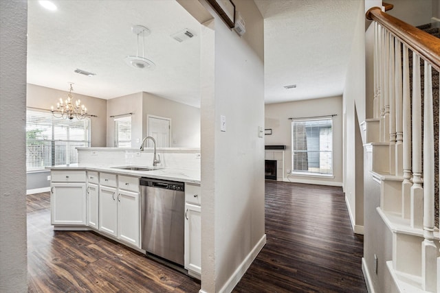 kitchen featuring sink, white cabinets, stainless steel dishwasher, hanging light fixtures, and dark wood-type flooring