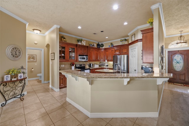 kitchen featuring light tile patterned floors, ornamental molding, appliances with stainless steel finishes, kitchen peninsula, and a breakfast bar area