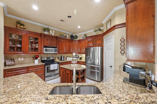 kitchen with light stone countertops, crown molding, sink, and stainless steel appliances