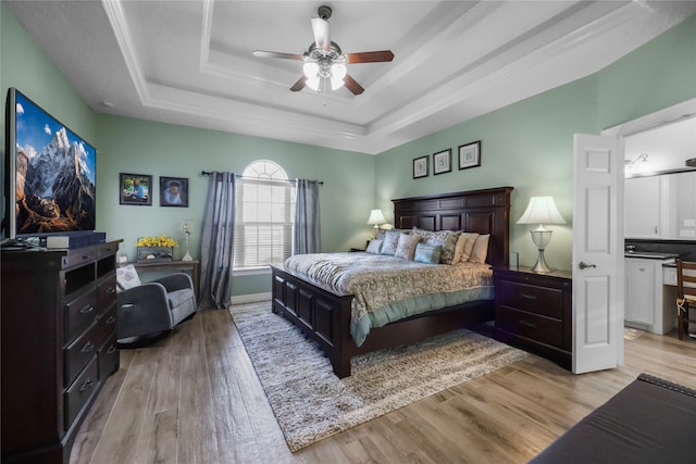 bedroom featuring a raised ceiling, ceiling fan, crown molding, and light wood-type flooring