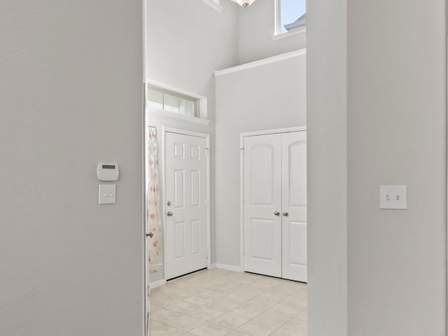 hall featuring a high ceiling and light tile patterned flooring