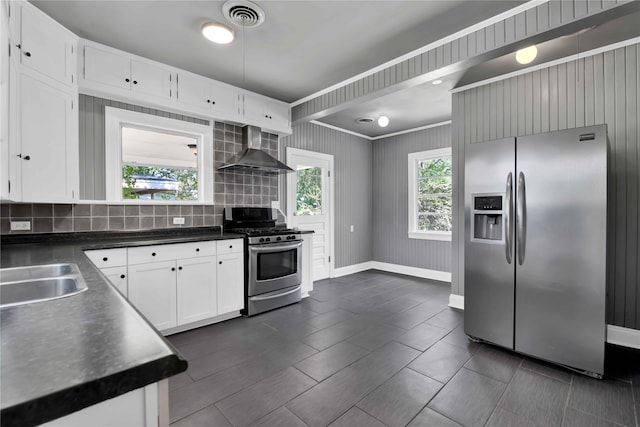 kitchen with appliances with stainless steel finishes, white cabinetry, tasteful backsplash, wall chimney exhaust hood, and sink