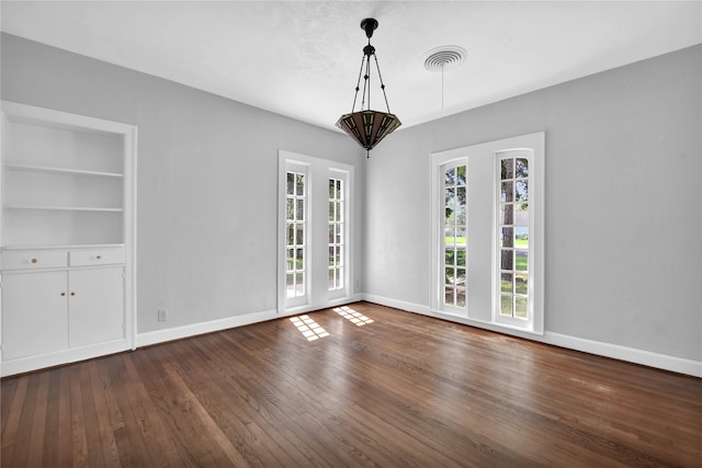 empty room featuring dark hardwood / wood-style floors and built in features