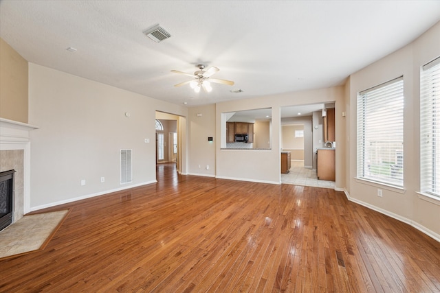 unfurnished living room featuring ceiling fan, a fireplace, and light hardwood / wood-style flooring