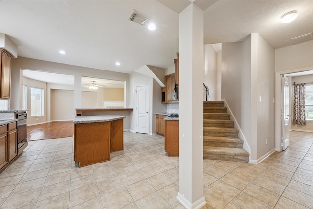 kitchen with a breakfast bar, light tile patterned floors, a center island, ceiling fan, and stainless steel dishwasher