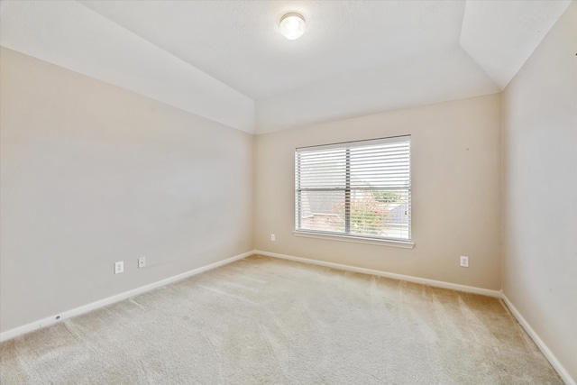 carpeted spare room featuring lofted ceiling