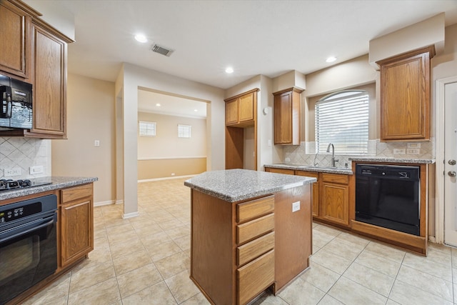 kitchen with decorative backsplash, black appliances, a center island, and sink