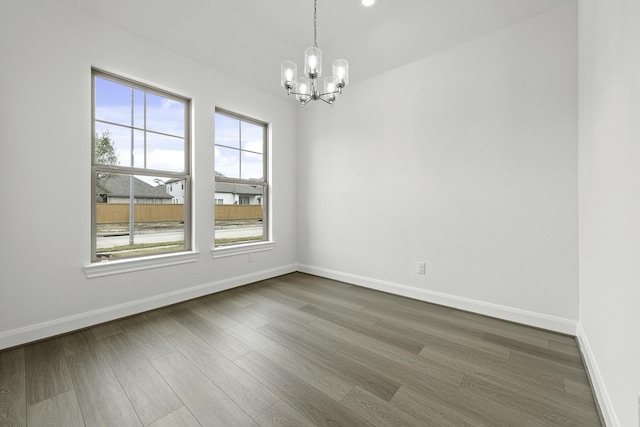 unfurnished room with baseboards, dark wood finished floors, and a chandelier