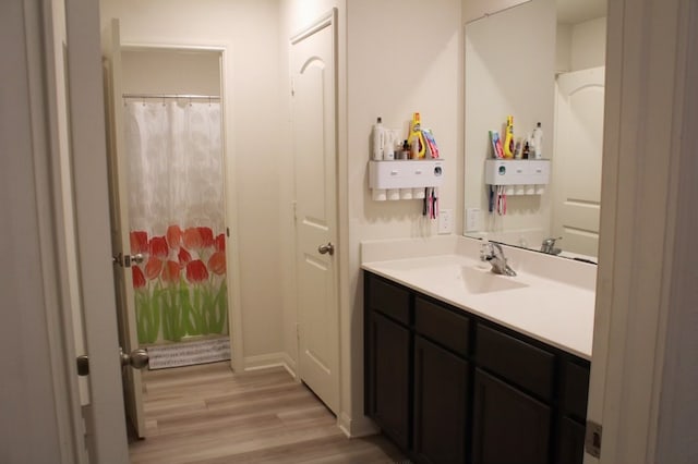 bathroom with wood-type flooring, a shower with curtain, and vanity