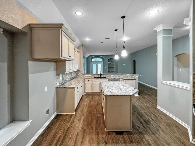 kitchen with hanging light fixtures, sink, kitchen peninsula, a kitchen island, and dark hardwood / wood-style floors