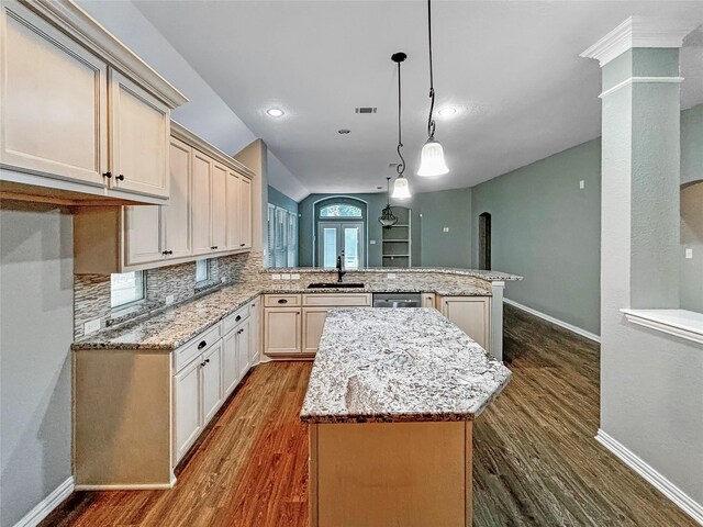 kitchen featuring hanging light fixtures, kitchen peninsula, sink, a kitchen island, and dark hardwood / wood-style floors