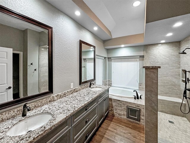 bathroom with independent shower and bath, lofted ceiling, vanity, and hardwood / wood-style floors