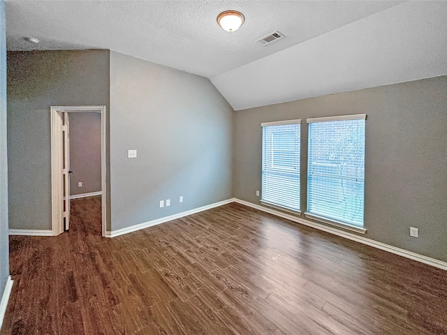 interior space featuring a textured ceiling, vaulted ceiling, and dark hardwood / wood-style flooring