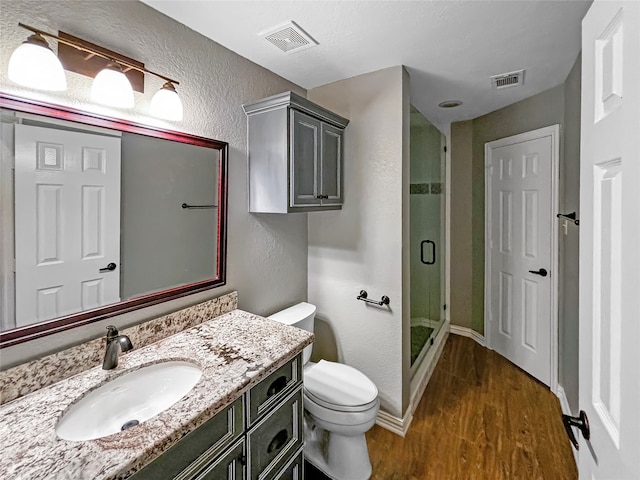 bathroom featuring hardwood / wood-style floors, vanity, toilet, and an enclosed shower